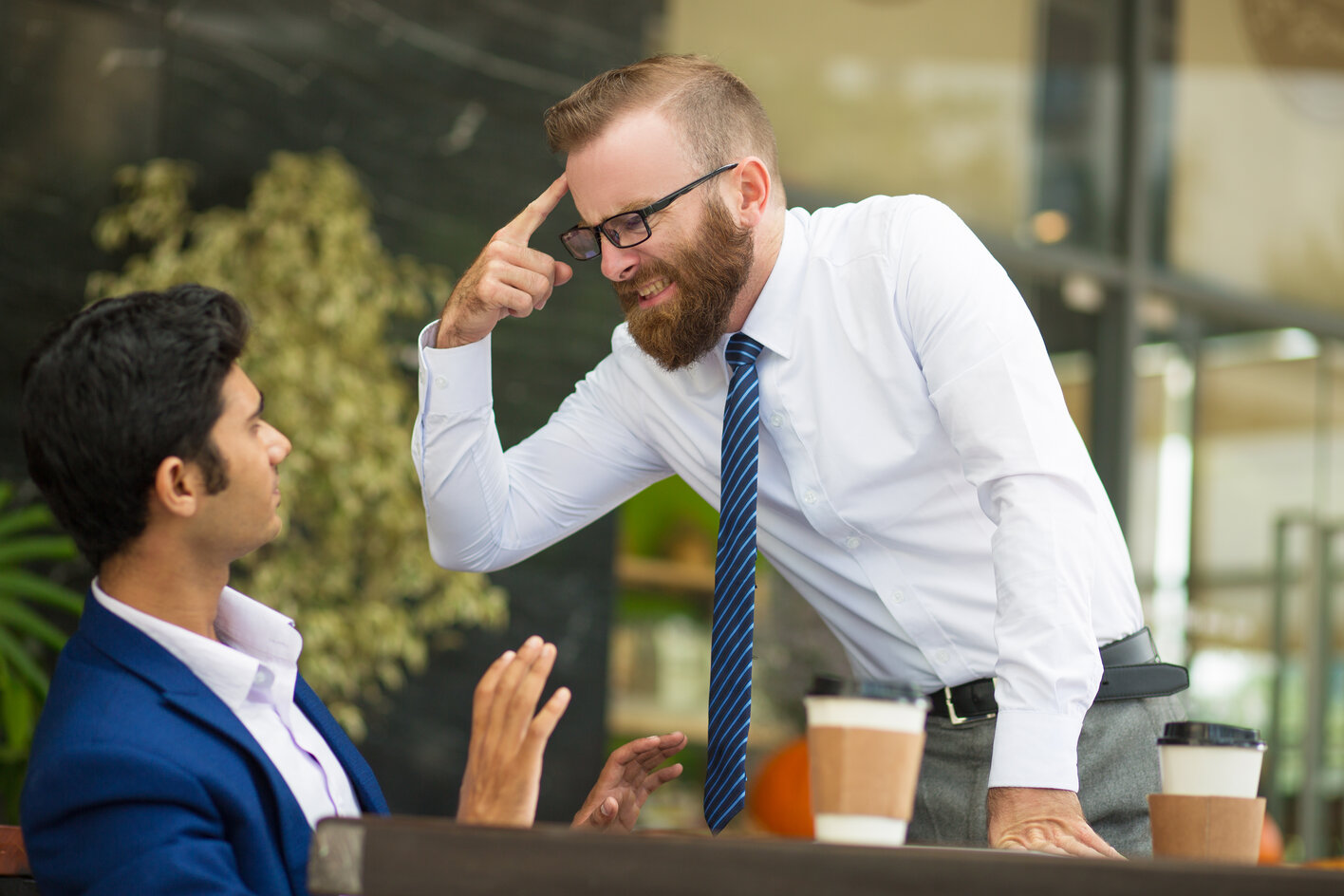 Boss yelling over an associate pointing at his head