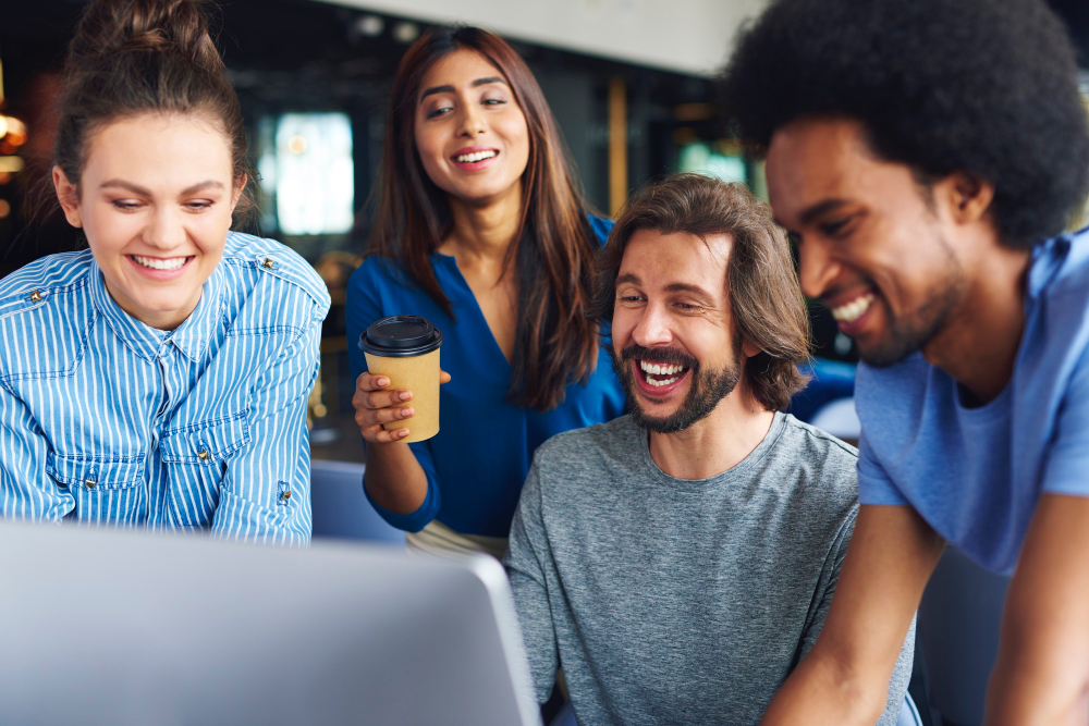 happy looking employees surrounding a laptop