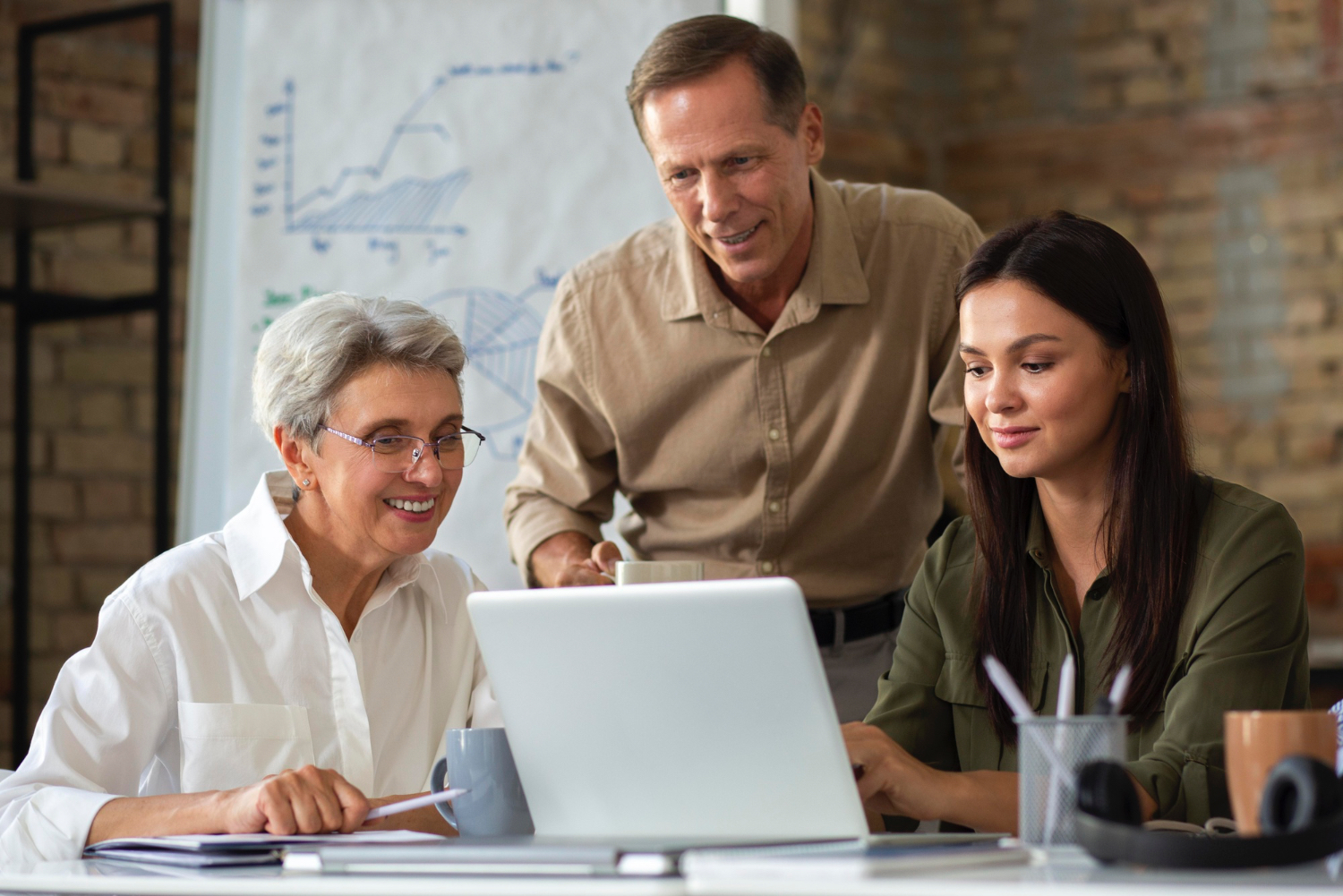 2 three employees belonging to different generations working around a laptop